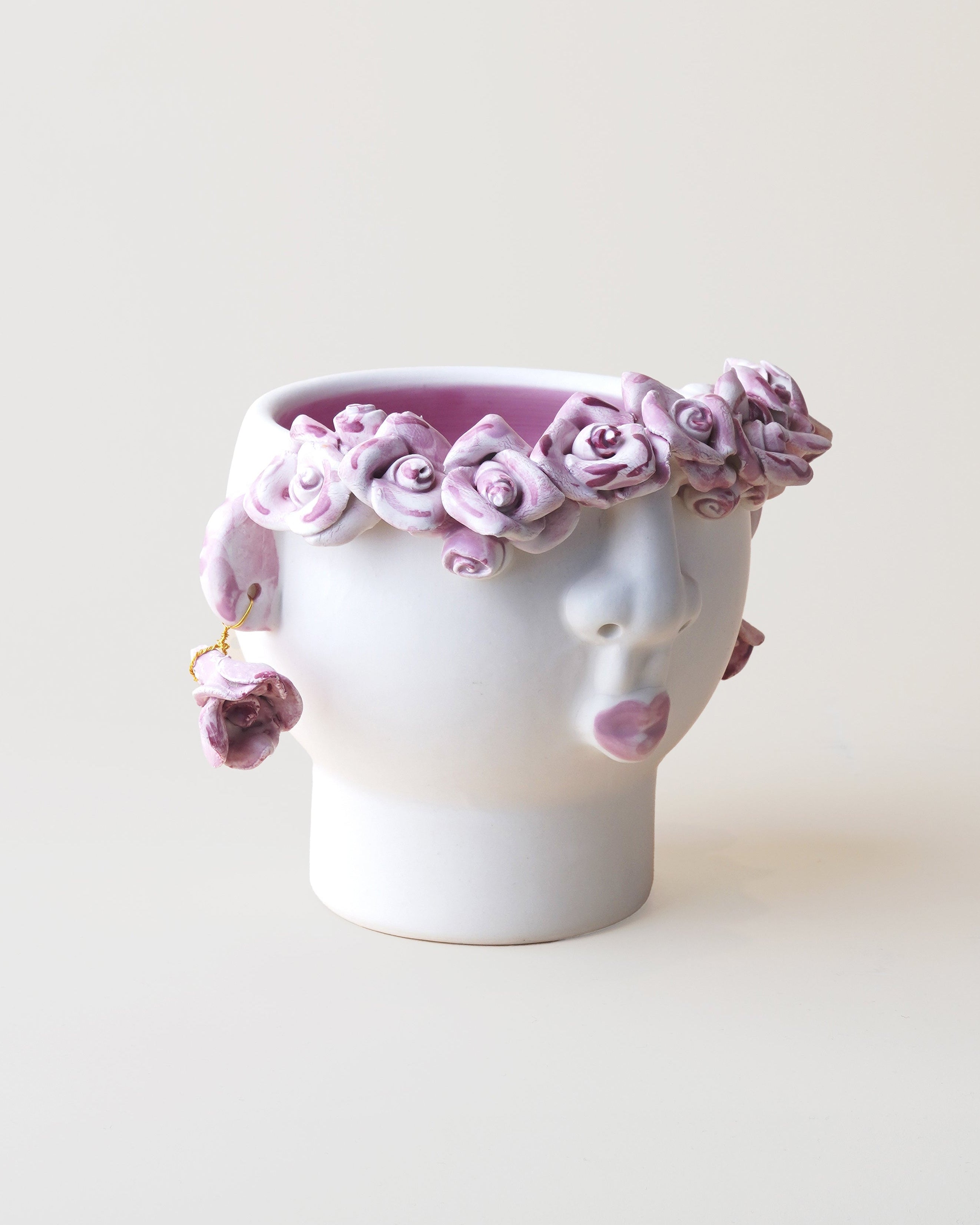 Ceramic vase shaped like a face with pink floral design on a white background
