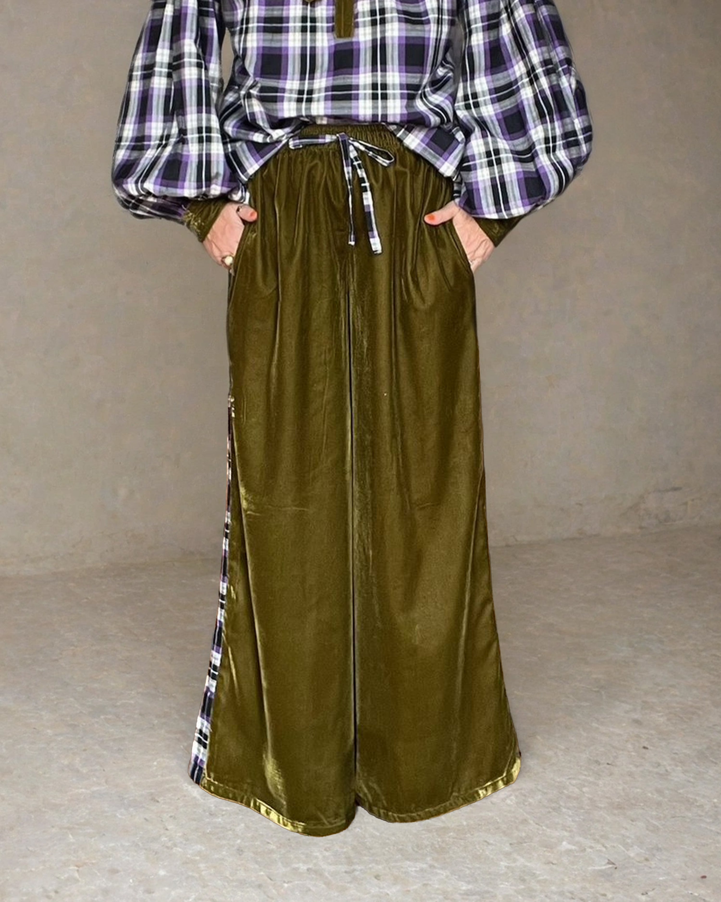Person wearing a plaid shirt and olive green wide-leg pants against a plain background