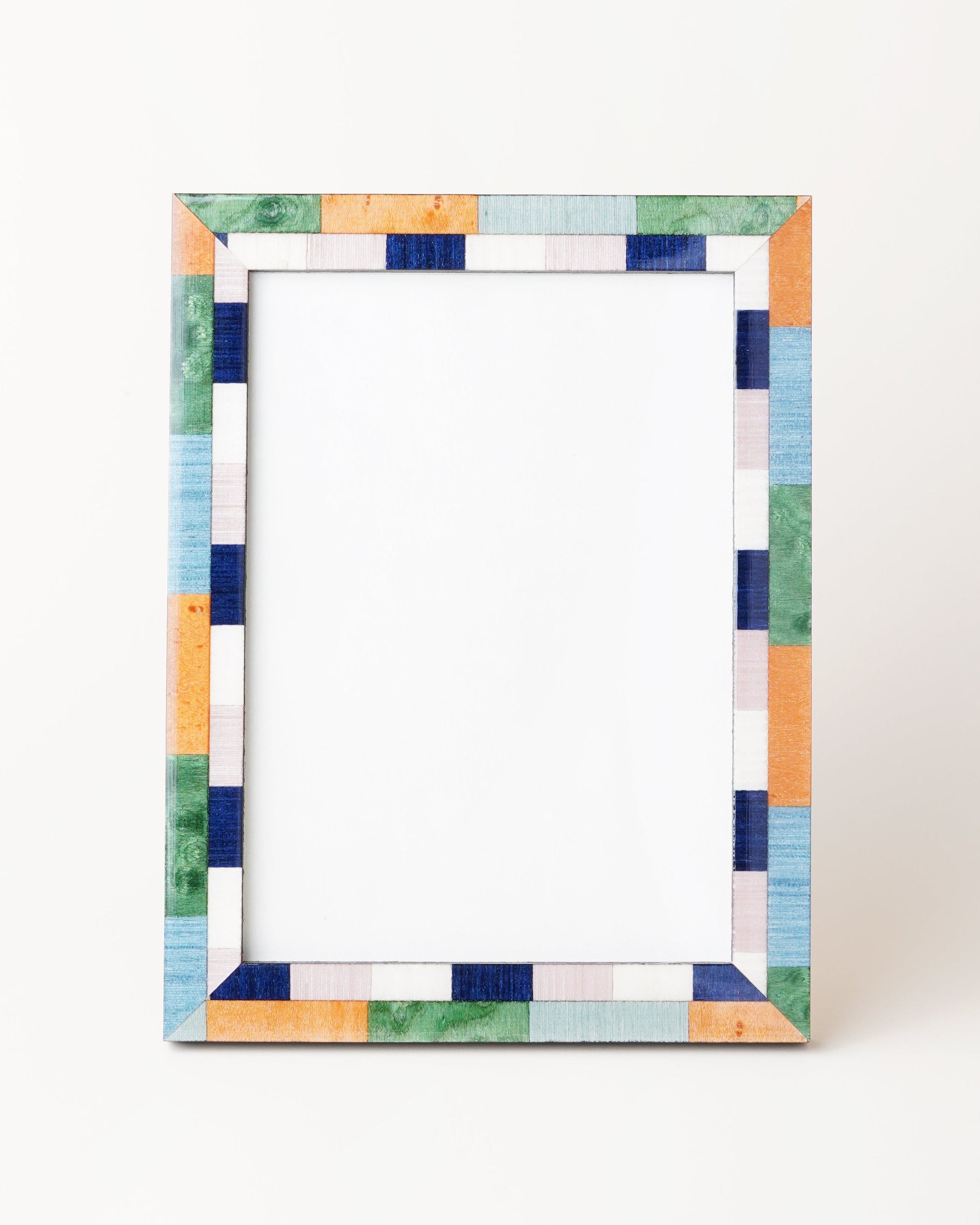 A picture frame with green, blue, and ochre colors, made of veneer, with a visible white backing.