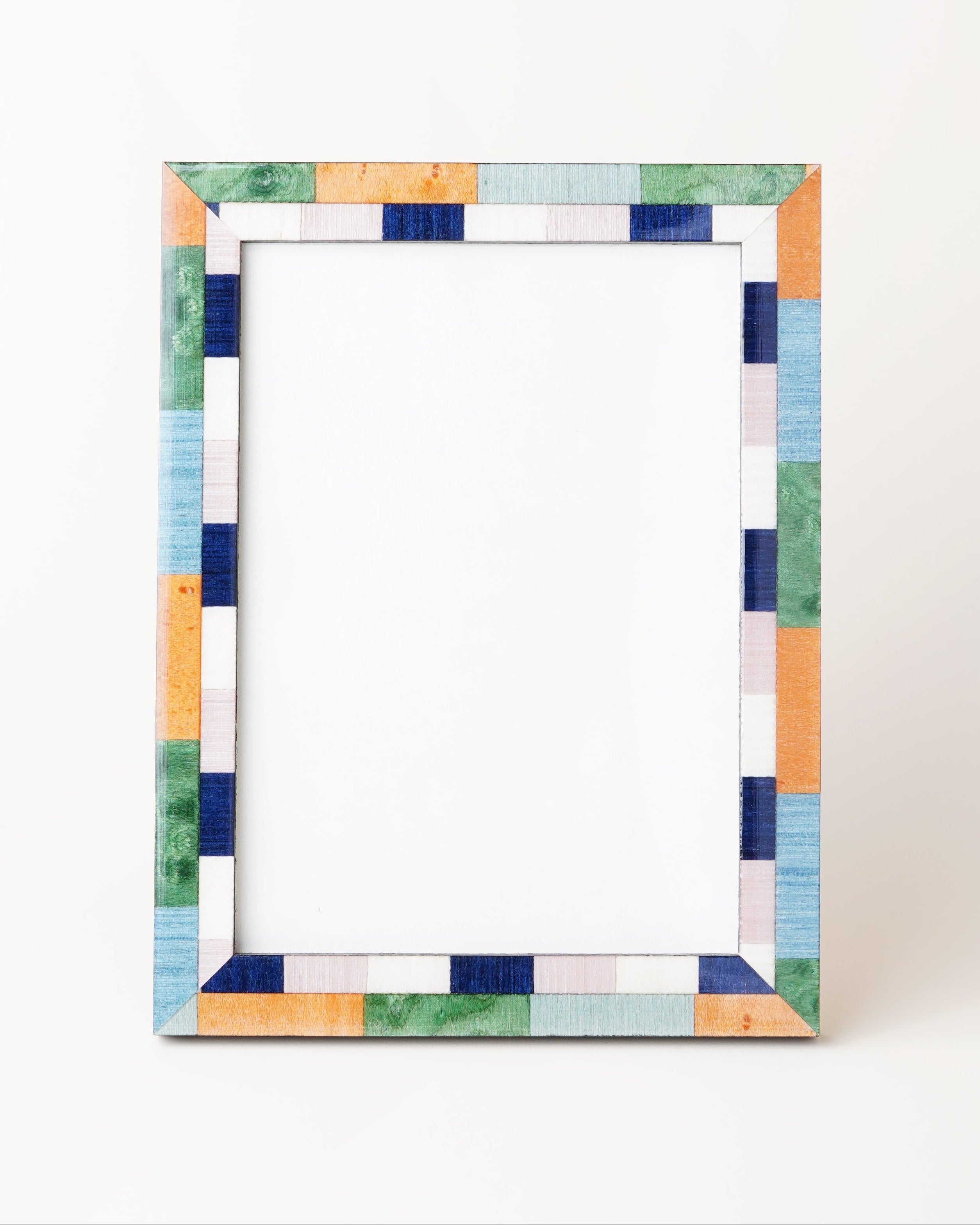 A picture frame with green, blue, and ochre colors, made of veneer, with a visible white backing.