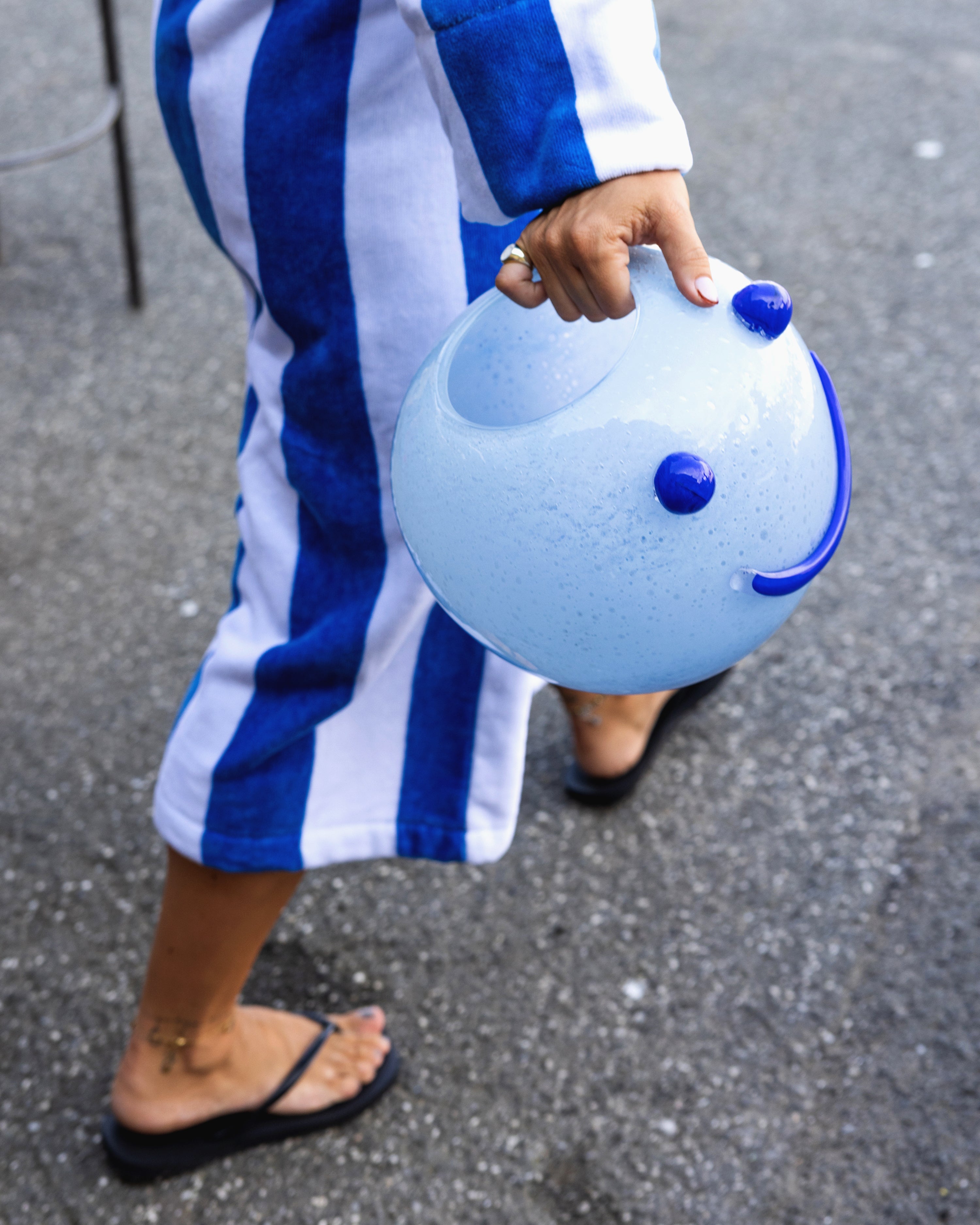 Person holding a blue smiley face vase with a striped outfit