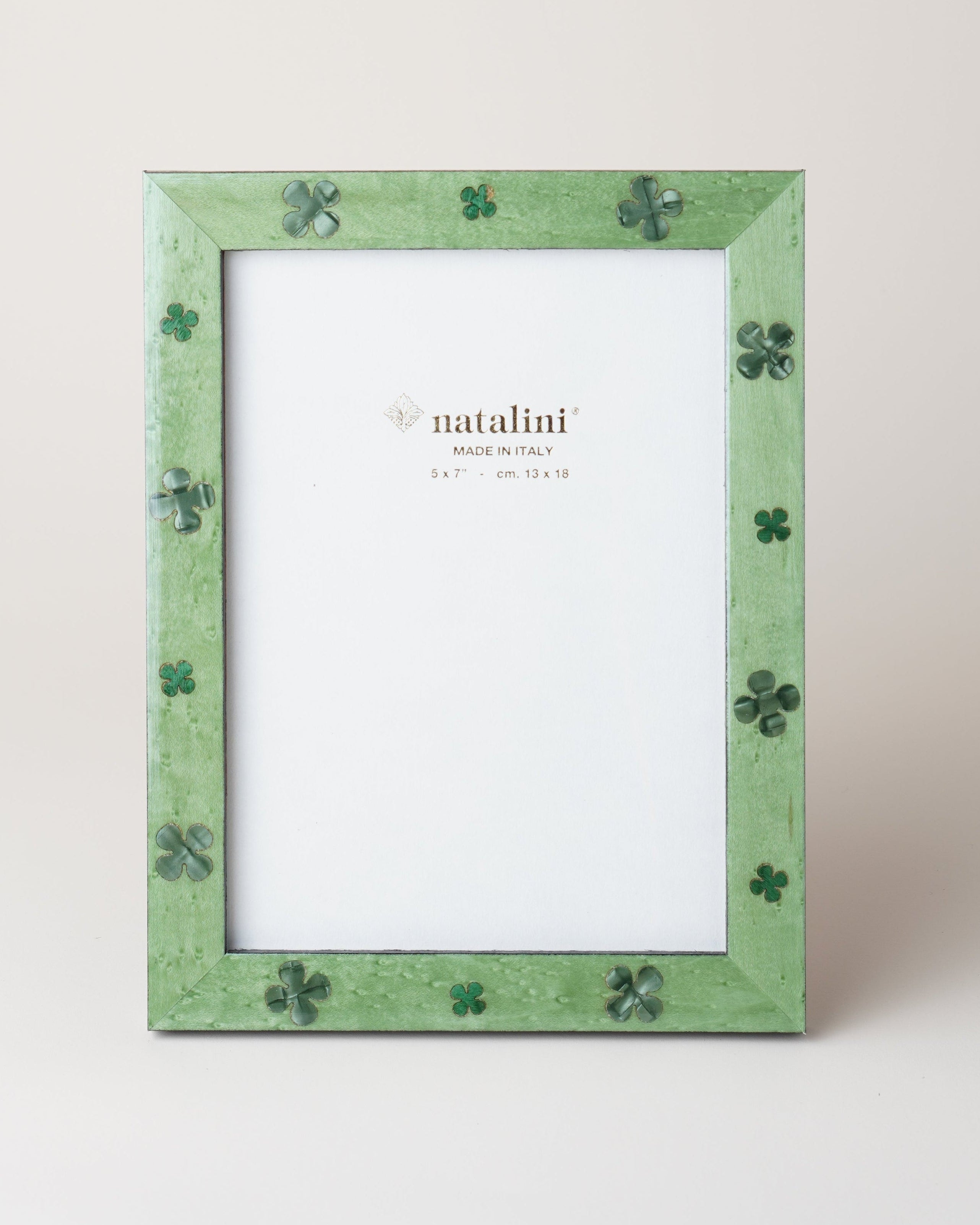 A green picture frame with a pattern of four-leaf clovers cut into the veneer, standing against a white background.