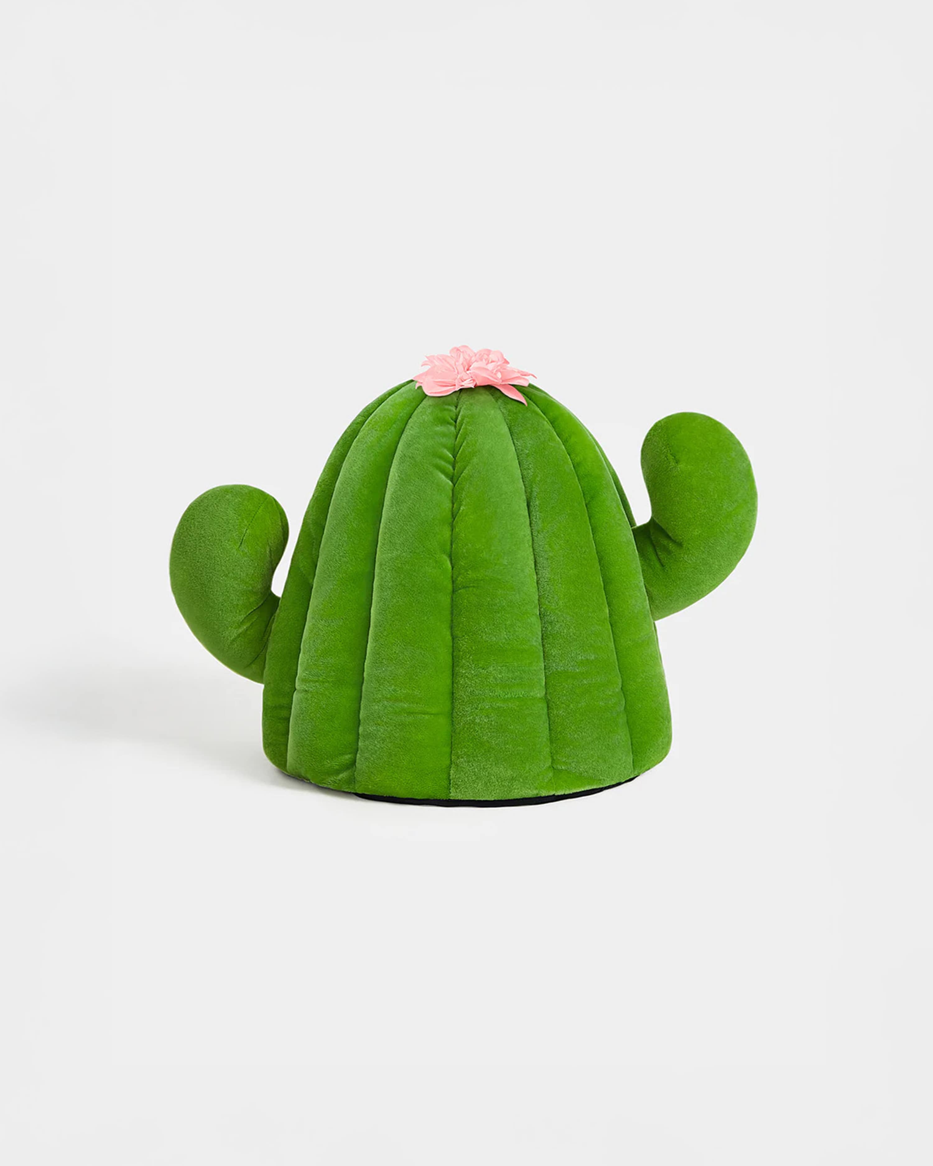 Green cactus-shaped pillow with a pink flower on a white background
