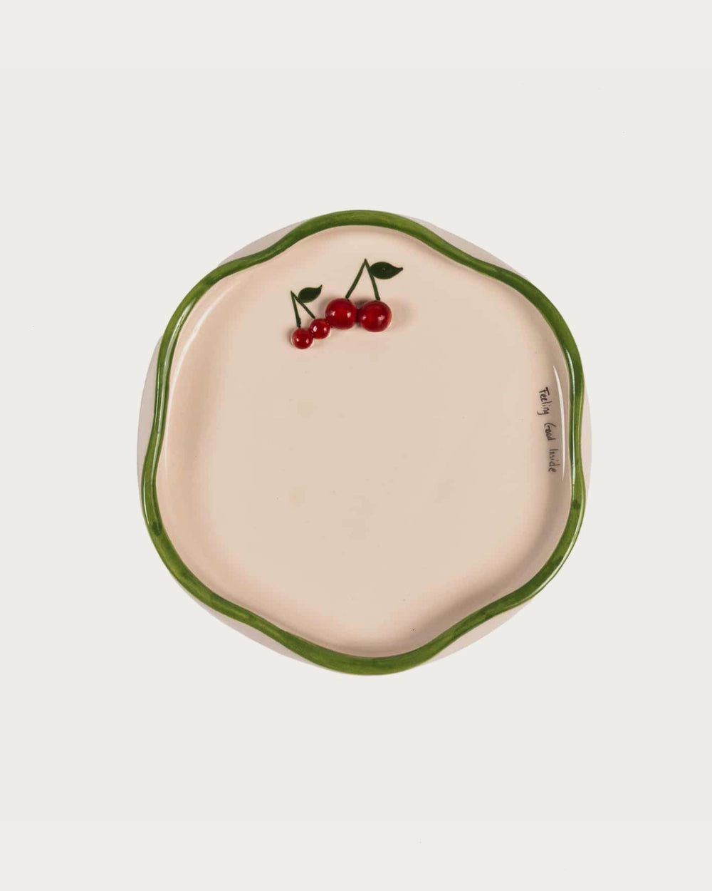 Ceramic dish with green rim and cherry design on a white background