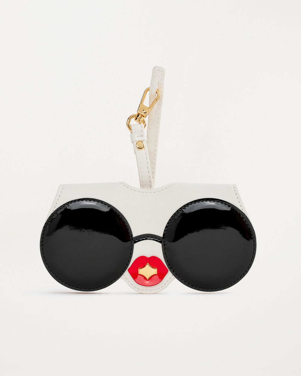 “Diva SunCover sunglasses case in white vegan leather with black round sunglasses face design and glossy red lips, inspired by CEO and designer Anne Dickhardt, gold-plated hardware”

