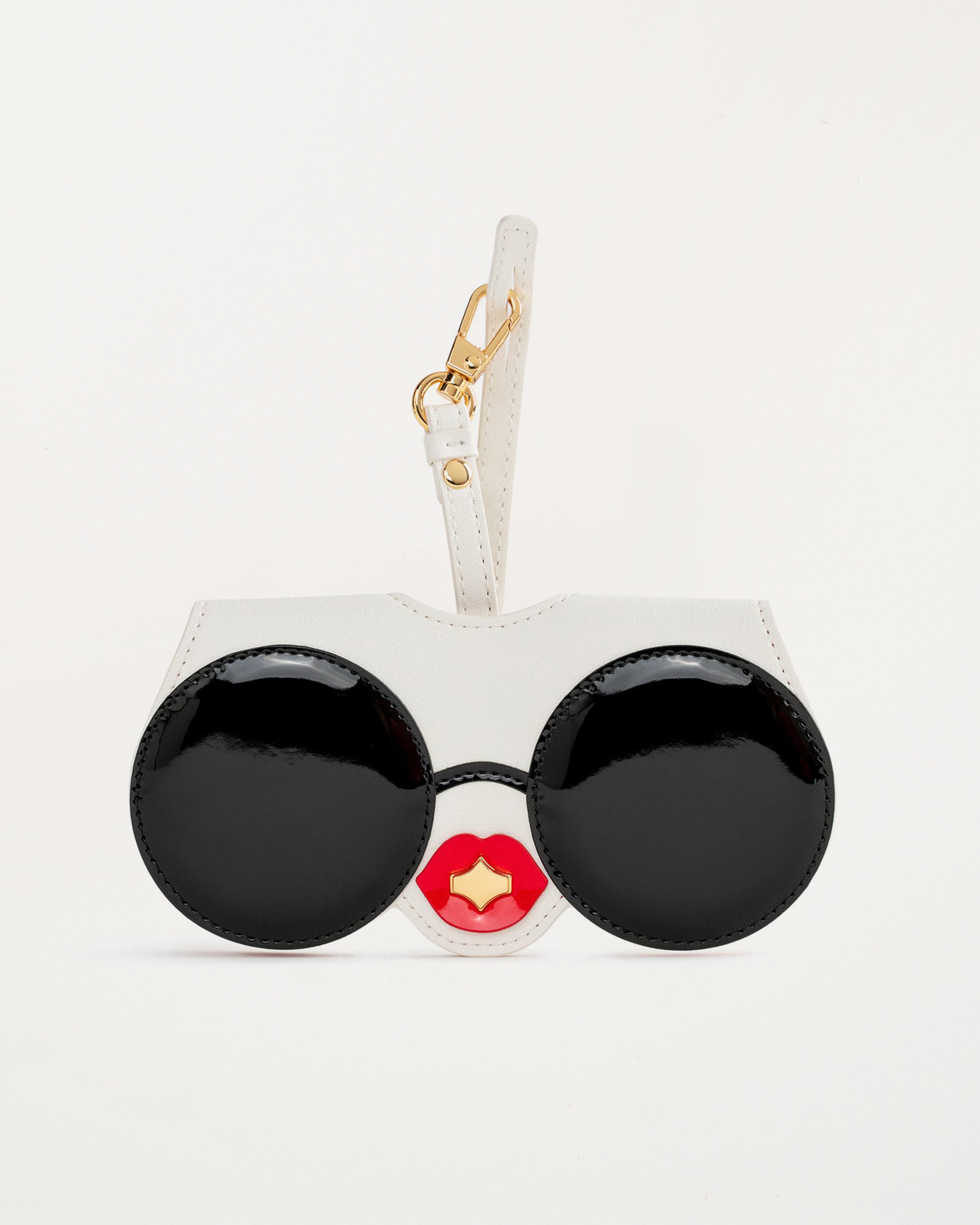 “Diva SunCover sunglasses case in white vegan leather with black round sunglasses face design and glossy red lips, inspired by CEO and designer Anne Dickhardt, gold-plated hardware”

