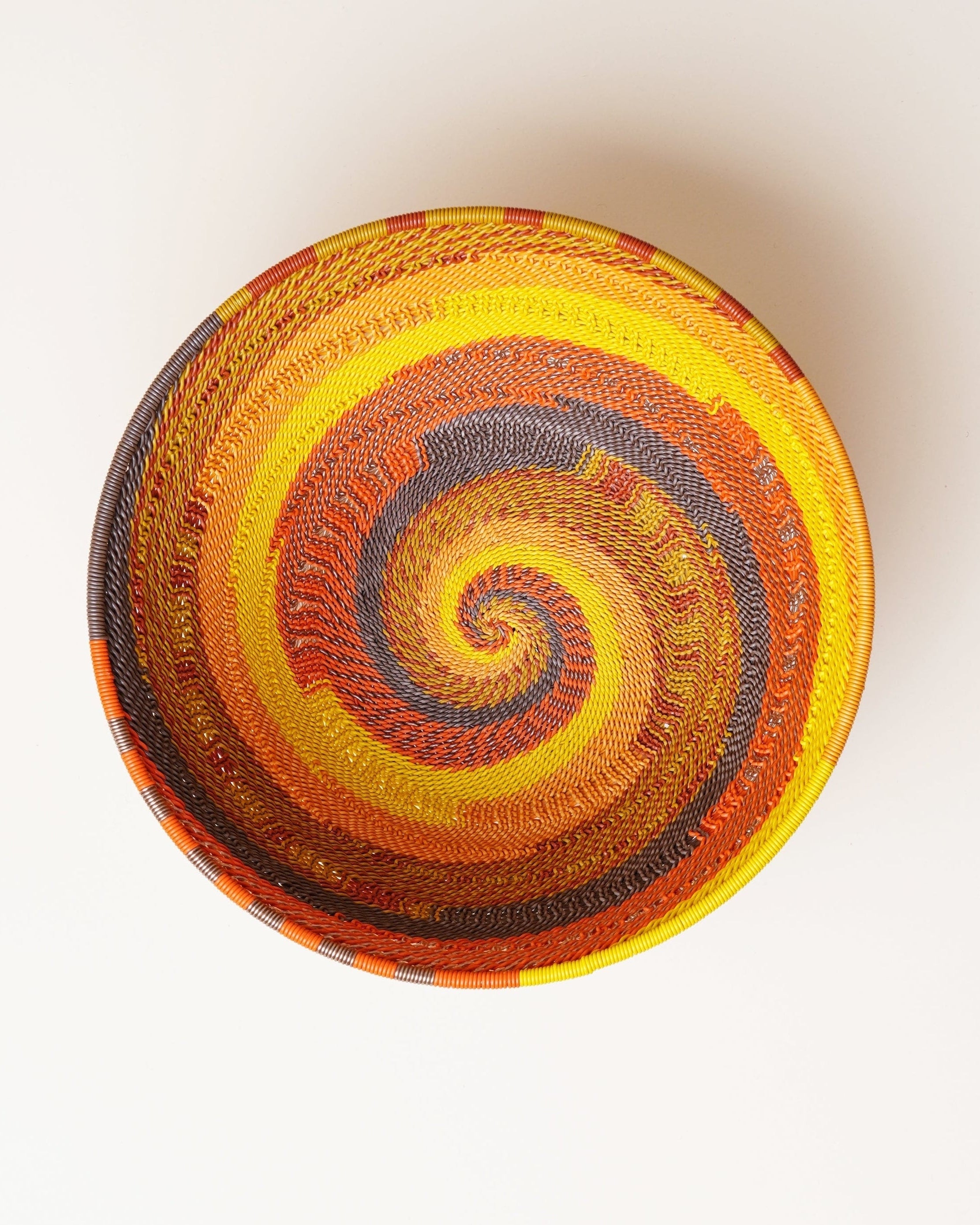 Colorful woven basket with a spiral pattern on a white background